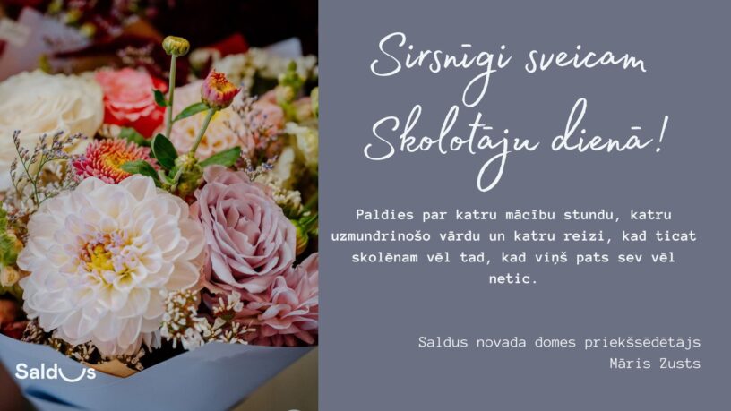Krāsains ziedu pušķis ar baltām dālijām un rozā rozēm attēla kreisajā pusē. Labajā pusē pelēks fons ar baltu tekstu: "Sirsnīgi sveicam Skolotāju dienā! Paldies par katru mācību stundu, katru uzmundrinošo vārdu un katru reizi, kad ticat skolēnam vēl tad, kad viņš pats sev vēl netic. Saldus novada domes priekšsēdētājs Māris Zusts." Attēla apakšējā kreisajā stūrī redzams "Saldus" logotips.